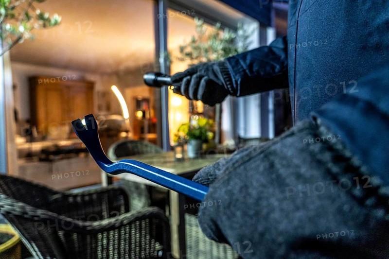 Symbolic image of a burglary, perpetrator spies on a flat from the garden side
