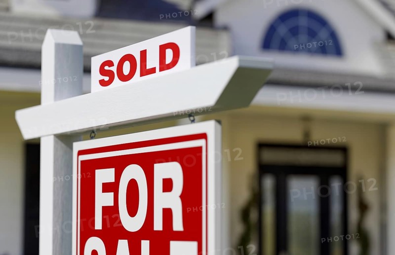 Sold for sale real estate sign in front of new house.