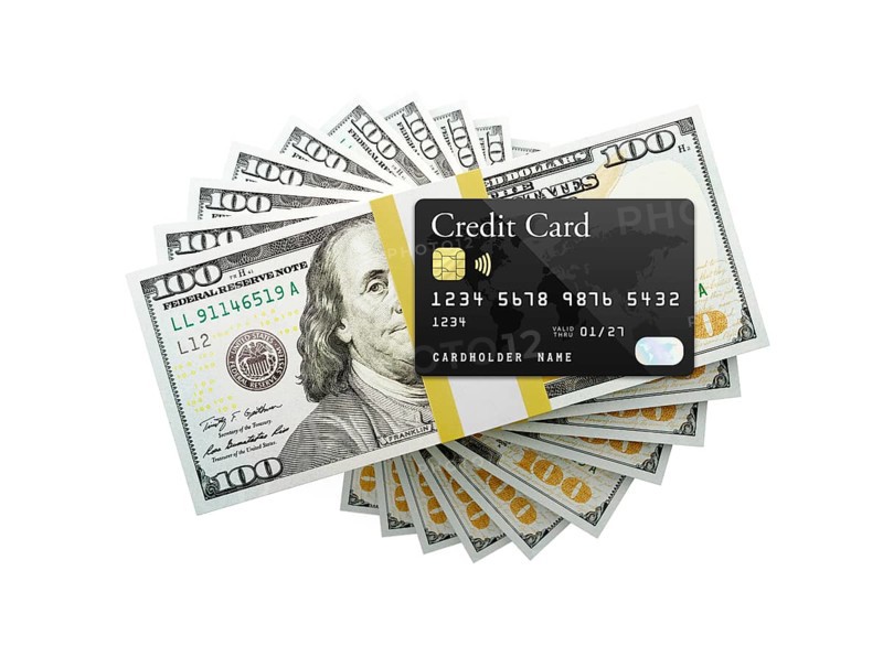 Overhead of credit card on top of one hundred thousand dollars spiralling stacks of one hundred dollar with red bow bills isolated on a white background.