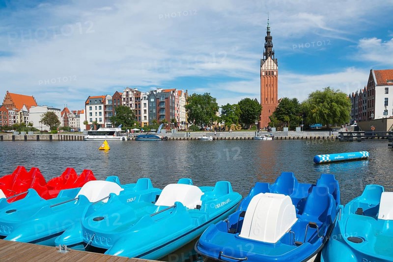 Colourful pedal boats on the river, buildings and a striking tower in the background, St. Nicholas Church, Elblag River, Elblag, Elbing, Warminsko-Mazurskie Voivodeship, Warminsko-Mazurskie, Poland, Europe