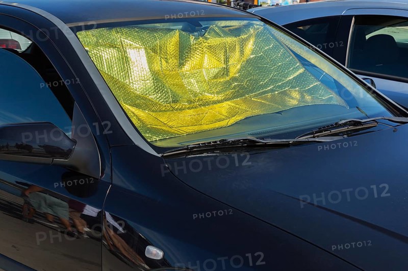 Car interior protected against heat buildup with foldable aluminum windshield sunshade and opened window on passenger side in summer, Sibenik, Croatia, Europe
