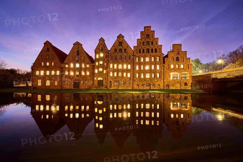 Salt storehouse, historic brick buildings, illuminated windows, symmetrical reflections on the water surface, evening blue hour with deep blue evening sky and cirrostratus clouds, Hanseatic city of Lübeck, independent city, Schleswig-Holstein, Germany, Europe