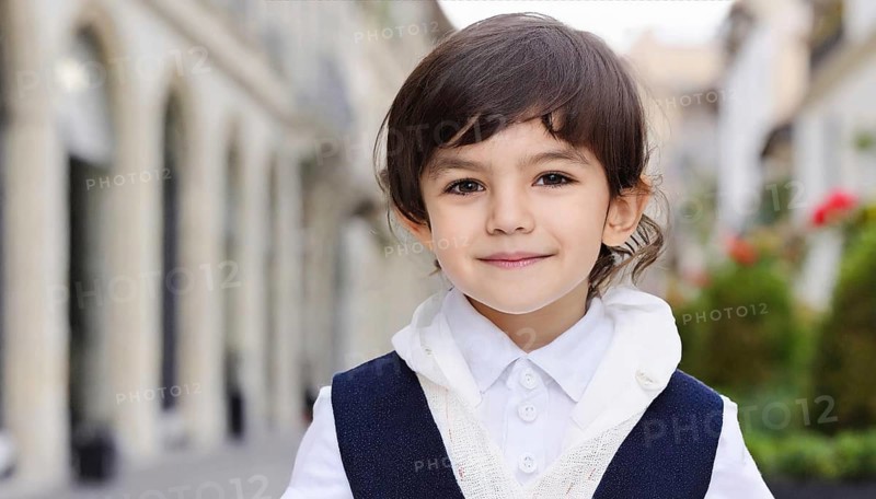A little boy with brown hair smiles confidently into the camera, wearing a shirt and waistcoat, AI generated, AI generated