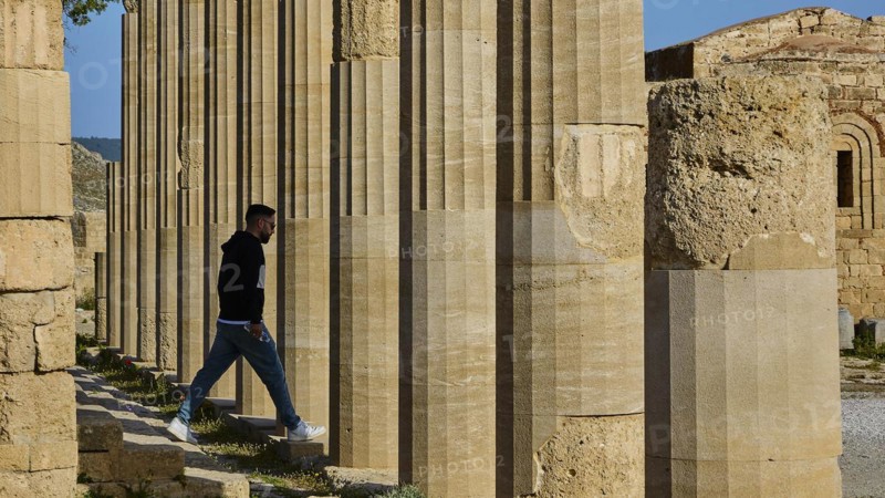 A man walks through ancient columns radiating tranquillity and historical significance, Acropolis of Lindos, Morning light, Propylaea, Lindos, Rhodes, Dodecanese, Greek Islands, Greece, Europe