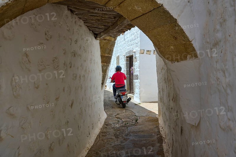 Motorcyclist riding through a narrow alley with whitewashed walls on a sunny day, Chora, main town Patmos, Patmos, Old Town, Dodecanese, Greek Islands, Greece, Europe