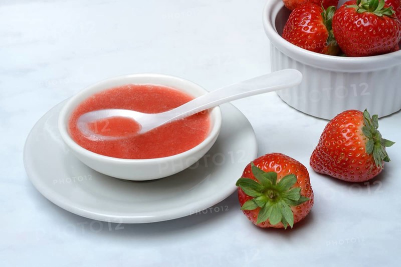 Strawberry sauce in small bowls and strawberries, strawberry coulis