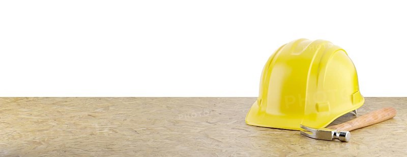 Yellow construction hard hat and hammer resting on particleboard banner isolated on a white background