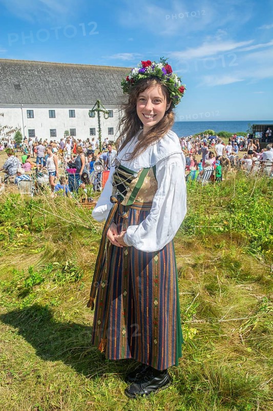 Young woman with a flower wreath on her head and dressed in folk costume from Smyge at a traditional midsummer celebration with dancing around a maypole at Smygehuk, Smygehamn, Trelleborg Municipality, Skåne County, Sweden, Scandinavia, Europe
