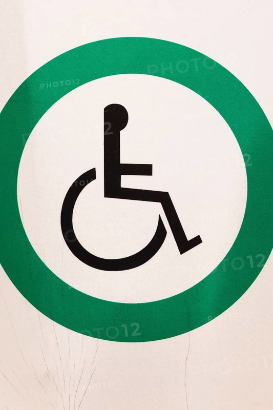 Close-up of posted white metal with black wheelchair in green circle Reserved Handicap Parking Spot pictogram notice sign outdoors, Quebec, Canada, North America