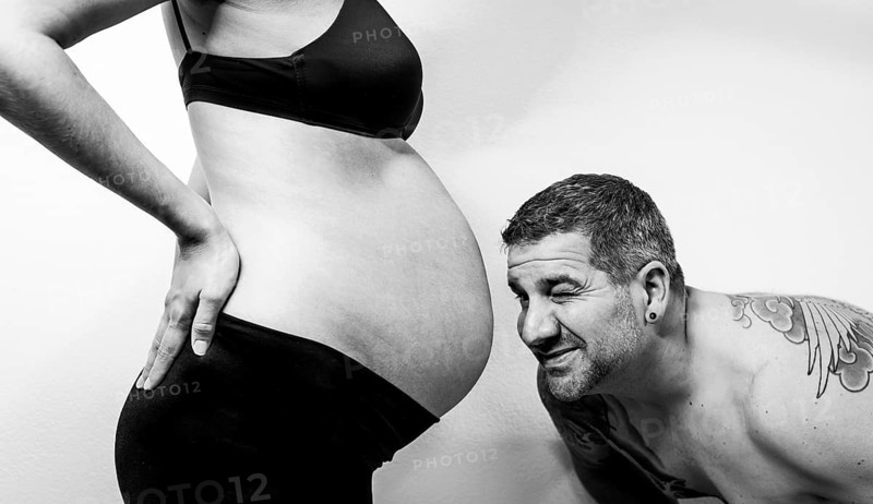 Black and white photo of a man looking at a woman's baby bump