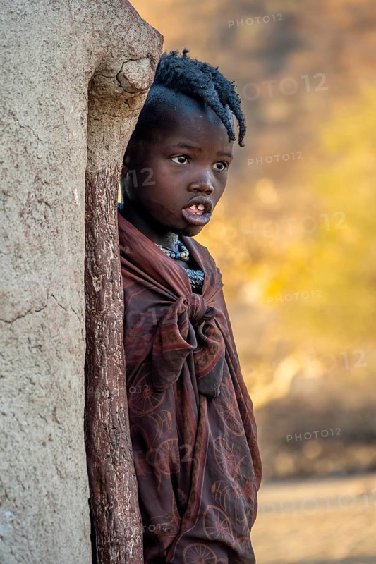 Himba girl leaning against a traditional mud hut, in the morning, traditional Himba village, Kaokoveld, Kunene, Namibia, Africa