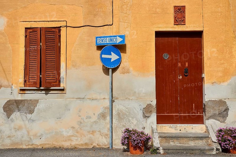 House wall, one-way street sign, brown door, brown shutters, flower pot, Rinella, town on the south coast, Salina, Aeolian Islands, Lipari Islands, Sicily. Italy