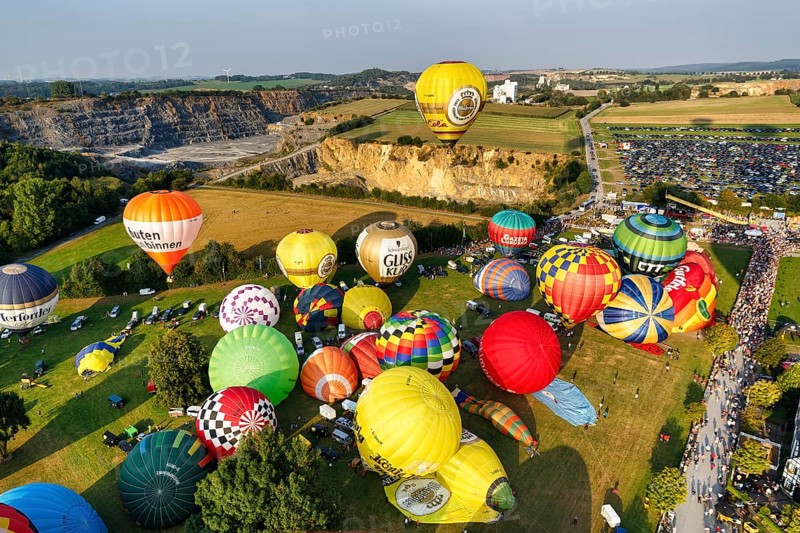 Colourful hot air balloons at mass launch, crowd on fairground, Hot Air Balloon Festival, 26th Warsteiner International Montgolfiade, aerial view, Warstein, Sauerland, North Rhine-Westphalia, Germany, Europe