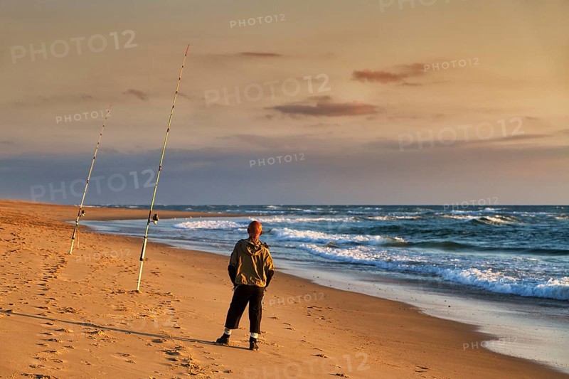 Surf fishing, angler standing with two rods on the beach, Soustons Plage, evening light, Silver Coast, Côte dArgent, Atlantic Ocean, Soustons, Landes, Nouvelle-Aquitaine, France, Europe