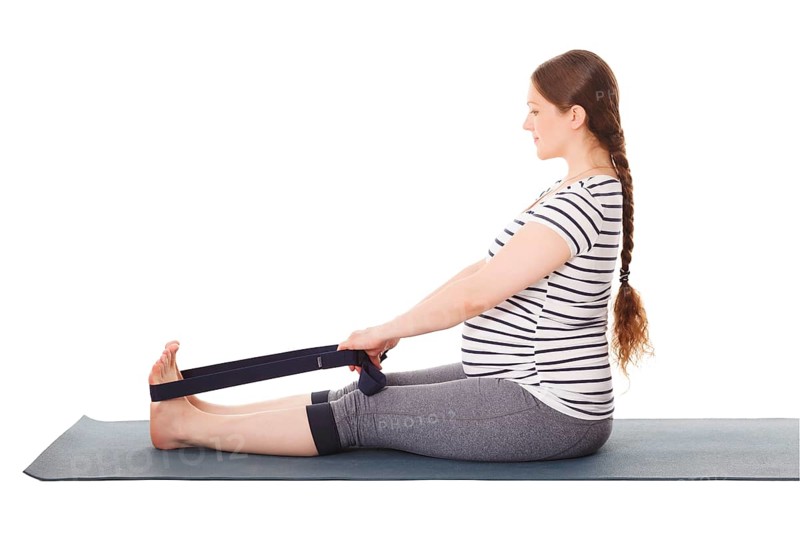Pregnancy yoga exercise, pregnant woman doing yoga asana Dandasana Staff pose with yoga strap isolated on white background