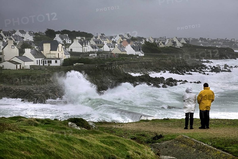 Tourists looking at winter storm at sea at Pors Poulhan, Plouhinec, Morbihan, Brittany, France, Europe