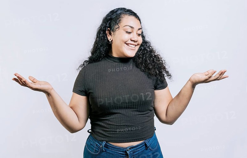 Smiling latin woman comparing with palms hands isolated. Happy girl balancing product with palms isolated