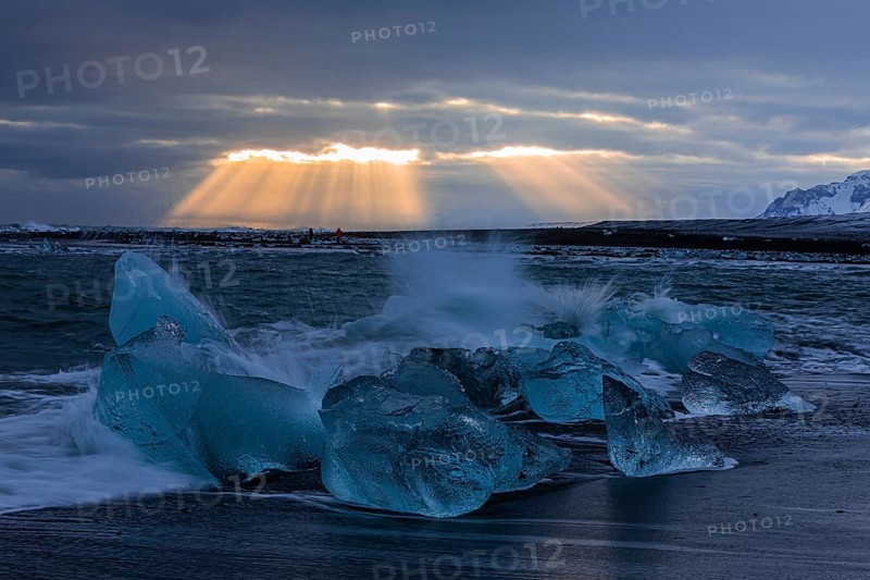 Waves breaking on icebergs on the black beach of Breidamerkursandur, sunset, near Jökullsarlon, Sudurland, Iceland, Europe