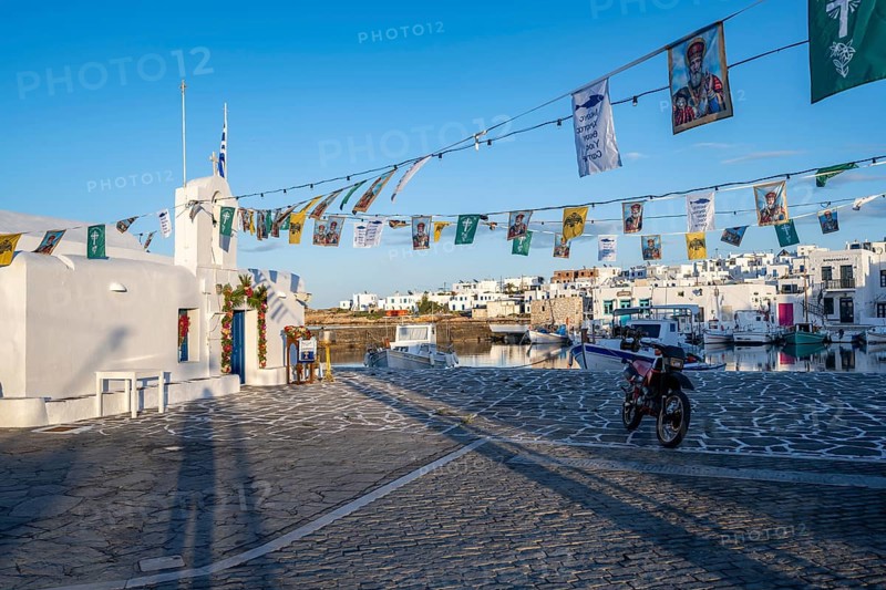 White Cycladic Greek Orthodox Church of Agios Nikolaos, decorated with flags, harbour of Naoussa, Naoussa, Paros, Cyclades, Greece, Europe