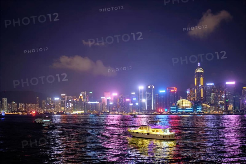 Hong Kong skyline cityscape downtown skyscrapers over Victoria Harbour in the evening illuminated with tourist boat ferries, Hong Kong, China, Asia