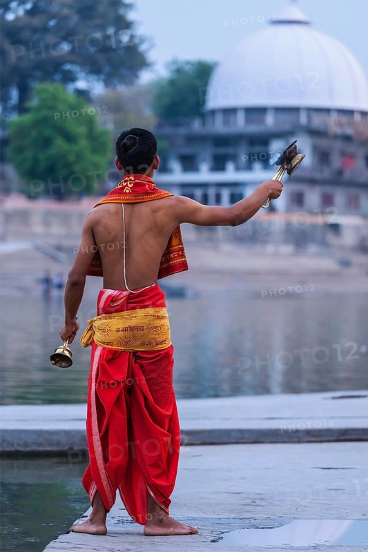 UJJAIN, INDIA, APRIL 23, 2011: Brahmin performing Aarti pooja ceremony on bank of holy river Kshipra. Aarti is Hindu religious ritual of worship, part of puja when light is offered to one or more deities