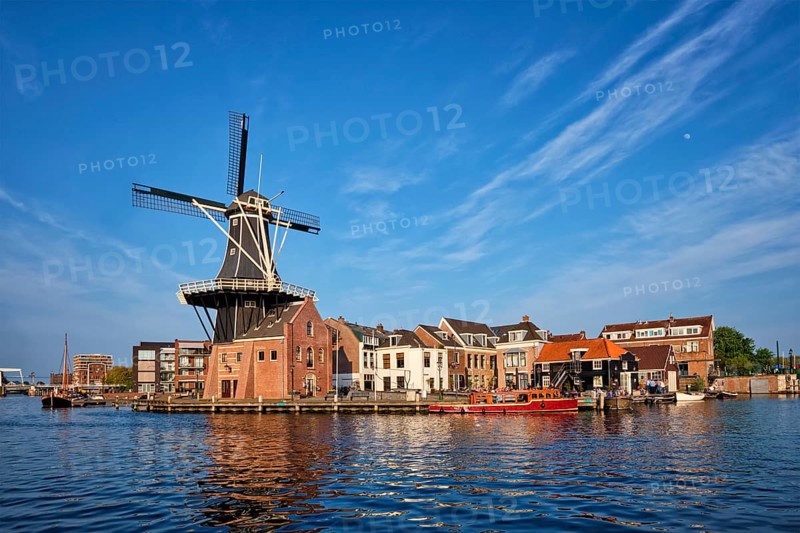 Harlem cityscape, landmark windmill De Adriaan on Spaarne river with boats. Harlem, Netherlands