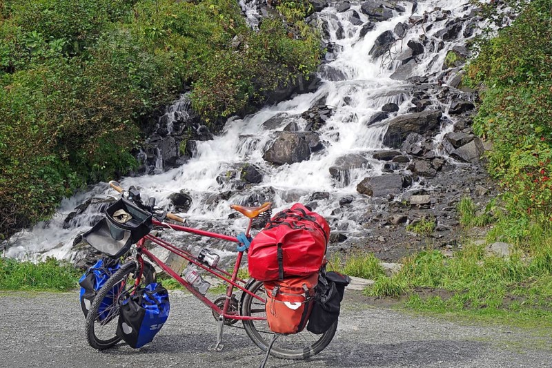 Bicycle with luggage in front of a waterfall, Chugach Mountains, Thompson Pass, Richardson Highway, Valdez, Alaska, USA, North America