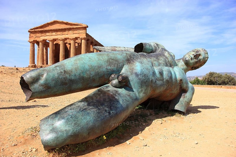 In the Parco Valle dei Templi di Agrigento, Unesco World Heritage Site, remains of the ancient city of Akragas in the Valley of the Temples of Agrigento, the Temple of Concordia with the sculpture of the dismounted Icarus by artist Igor Mitorgi, installed in 2012, Sicily, Italy, Europe