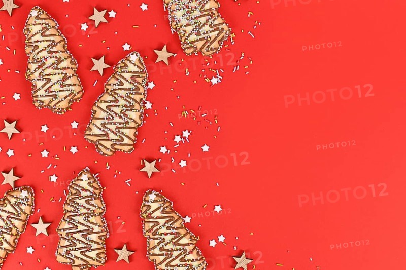 Christmas tree shaped cookies with sugar sprinkles on red background