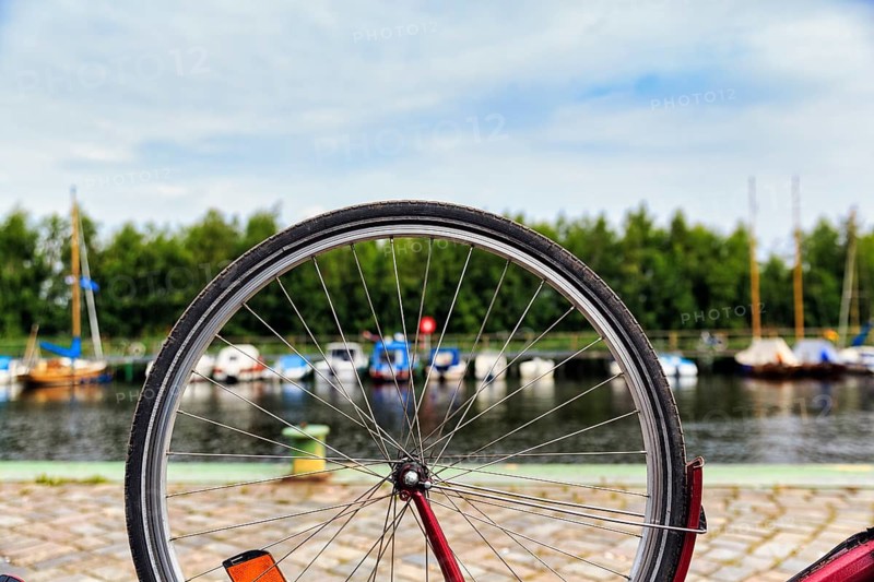 View through the spokes of a bicycle at boats on the river, symbolic image, repairing a bicycle, bicycle tour, Baltic Sea Coast Cycle Route, Greifswald, Germany, Europe