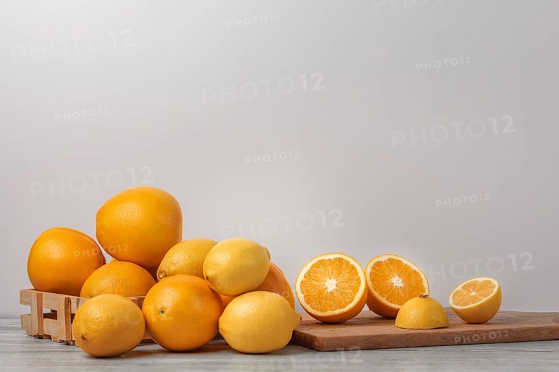 Basket and wooden board with oranges and lemons, vitamin C, light background, copy room