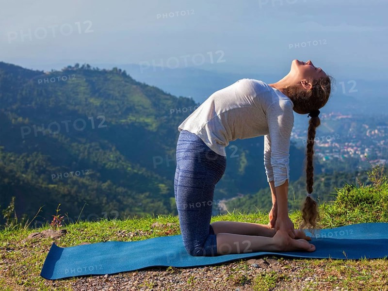 Yoga, outdoors young beautiful slender woman yoga instructor doing camel pose Ustrasana asana exercise outdoors in mountains in the morning