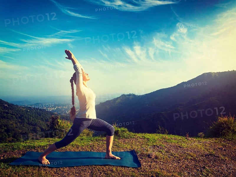 Yoga outdoors, sporty fit woman doing yoga asana Virabhadrasana 1, Warrior pose posture outdoors in Himalayas mountains in the morning. Vintage retro effect filtered hipster style image