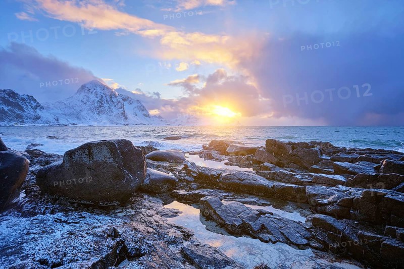 Beach of Norwegian sea on rocky coast in fjord on sunset in winter. Vareid beach, Lofoten islands, Norway, Europe