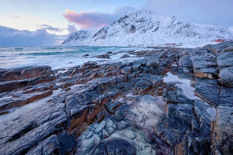 Beach of Norwegian sea on rocky coast in fjord on sunset in winter. Vareid beach, Lofoten islands, Norway, Europe