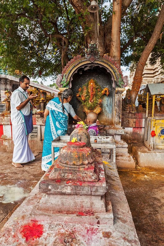 MADURAI, INDIA, FEBRUARY 16, 2013: Indian pilgrim family worshipping Hindu god Ganesh in famous Meenakshi Amman Temple, historic Hindu temple located in temple city Madurai