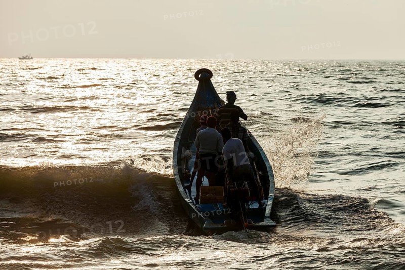 CHENNAI, INDIA, FEBRUARY 10, 2013: Group of Indian fishermen going into the sea on boat for fishing on sunrise