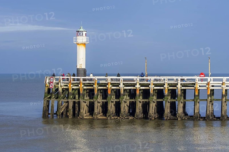 Sea anglers with large fishing rods casting their lines from wooden pier, jetty at the Nieuwpoort, Nieuport harbour entrance along the Belgian North Sea coast in winter, West Flanders, Belgium, Europe
