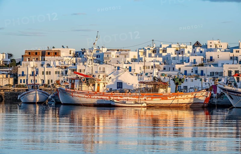 View of Naoussa, Fishing boats in the harbour at sunset, reflected in the sea, White Cycladic houses, Naoussa, Paros, Cyclades, Greece, Europe