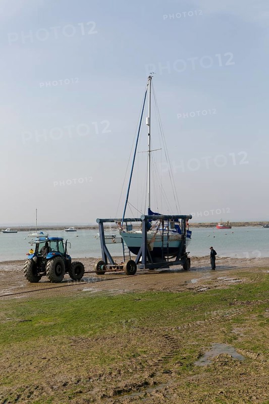 Tractor launching boat in cradle, River Blackwater estuary, West Mersea, Mersea Island, Essex, England, UK
