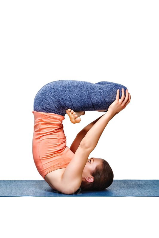 Sporty fit yogini woman practices inverted yoga asana Urdhva padmasana, lifted lotus pose isolated on white