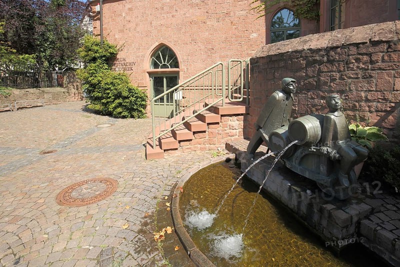 Ornamental fountain with two figures, wheelbarrows loaded with barrels and local history museum in Gelnhausen, museum of local history, Gelnhausen, Hesse, Germany, Europe