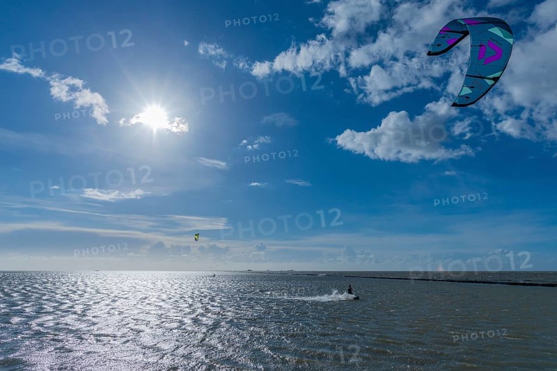 Kitesurfing on the North Sea, Lüttmoorsiel, Reußenköge, on the horizon Hallig Nordstrandischmoor, Lorendamm, backlight, wind force 6, blue sky, North Frisia, Schleswig-Holstein, Germany, Europe