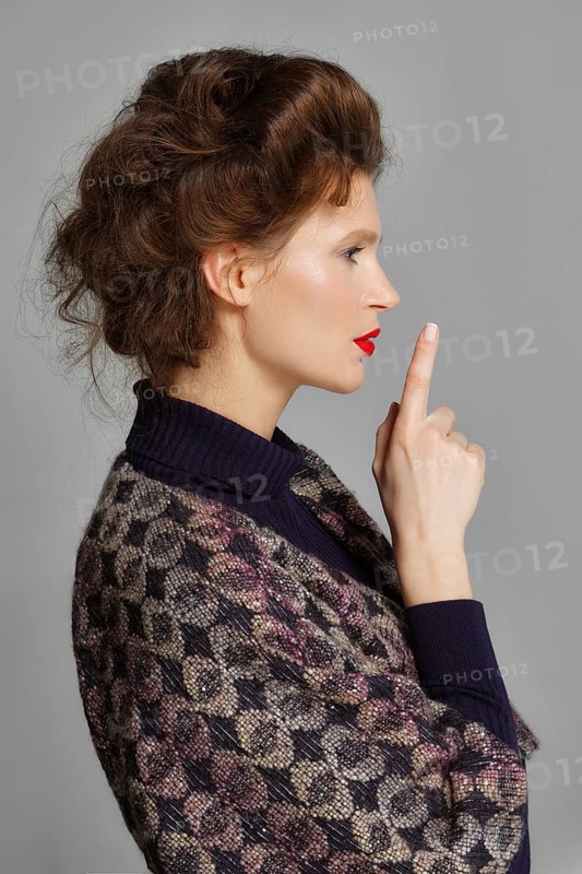 Portrait of a beautiful sexy fashion model pointing her finger up. Wedding make up and hair. Red lips, blue eyes