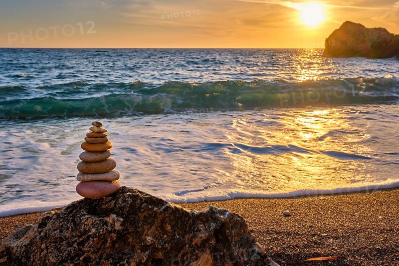 Cairn stack of stones pebbles cairn on the beach coast of the seaon sunset. Agios Ioannis beach, Milos island, Greece, Europe