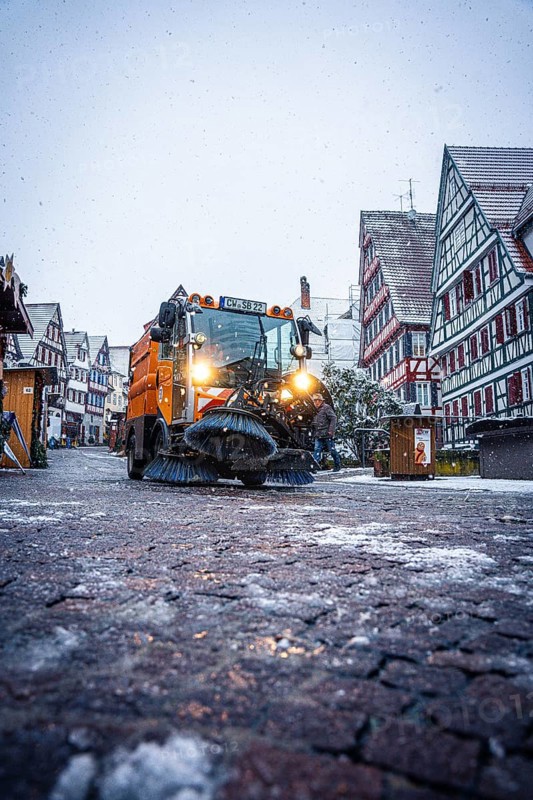 Clearing vehicle on a snow-covered road at a Christmas market at dusk, Black Forest, Calw, Germany, Europe