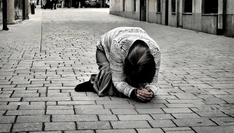 Social hardship, Torn beggar woman with poor clothes in humble posture kneeling on the street, KI generated, AI generated