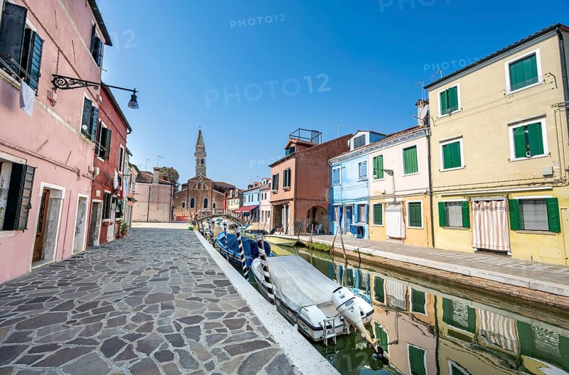 Colourful houses on the canal with reflection, canal with boats and colourful house facades, in the background church tower of the Chiesa Parrocchiale di San Martino Vescovo, Burano Island, Venice, Veneto, Italy, Europe
