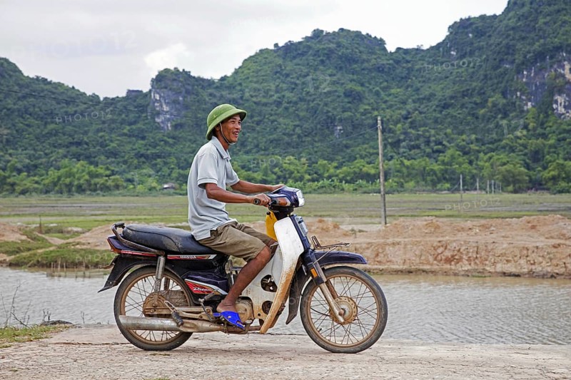 Happy Vietnamese man riding Honda Dream II motorcycle, motorbike in the countryside, Ninh Bình Province, Vietnam, Asia