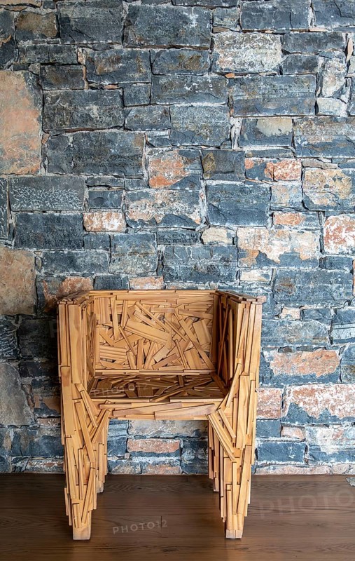 Designer chair in front of a stone wall, Crete, Greece, Europe